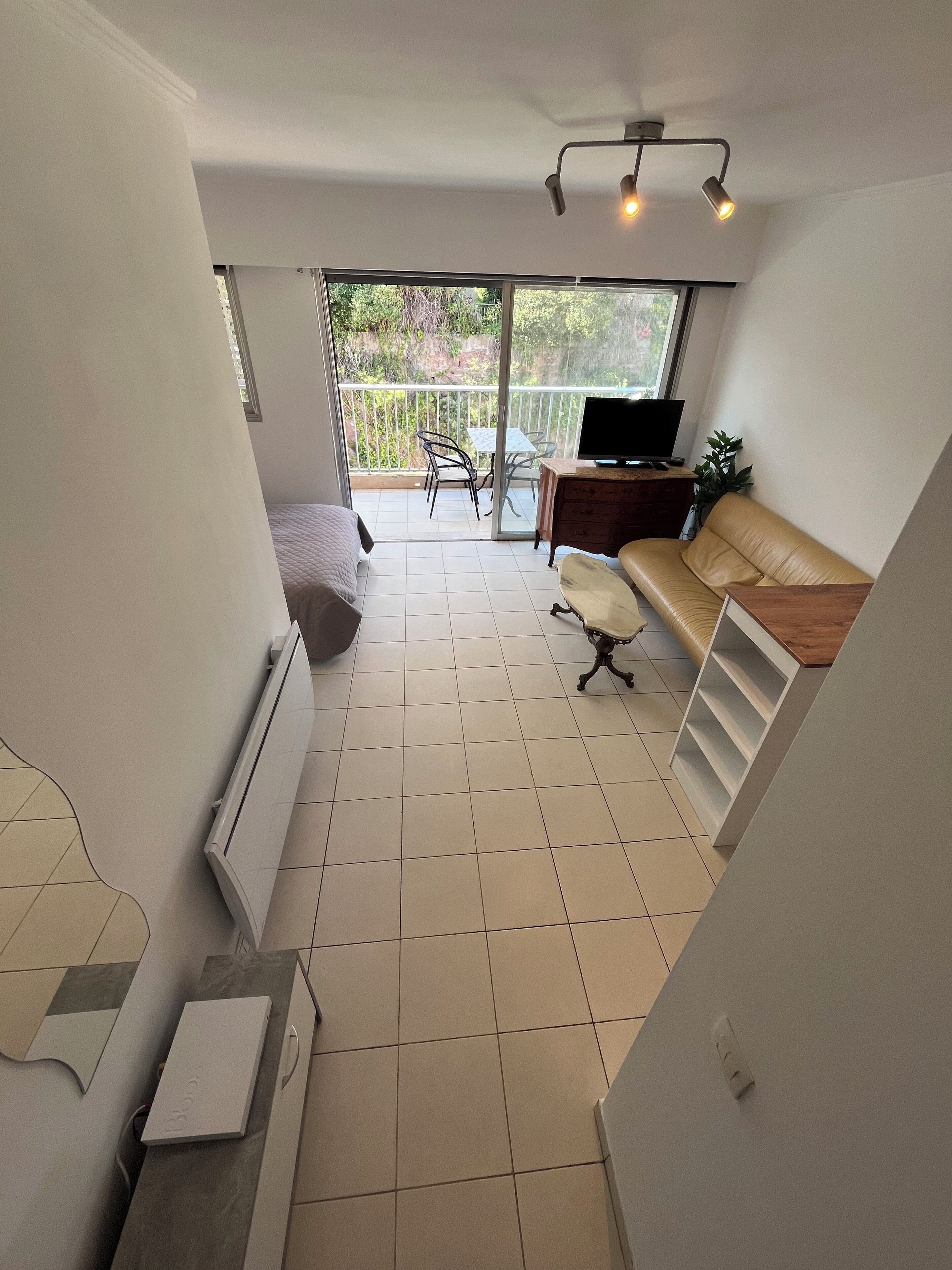 Una habitación amplia con balcón, sofá, televisor y zona de comedor.