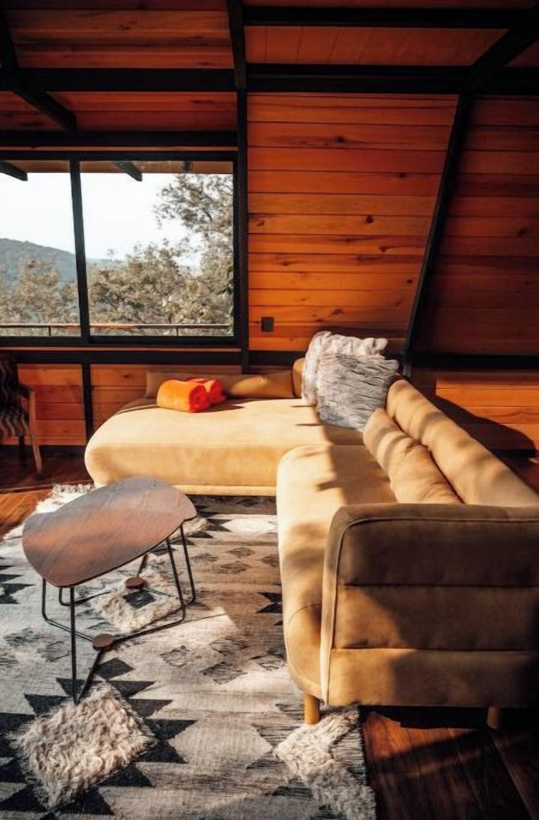 A cozy room with a sofa, ottoman, and a window overlooking a natural landscape.