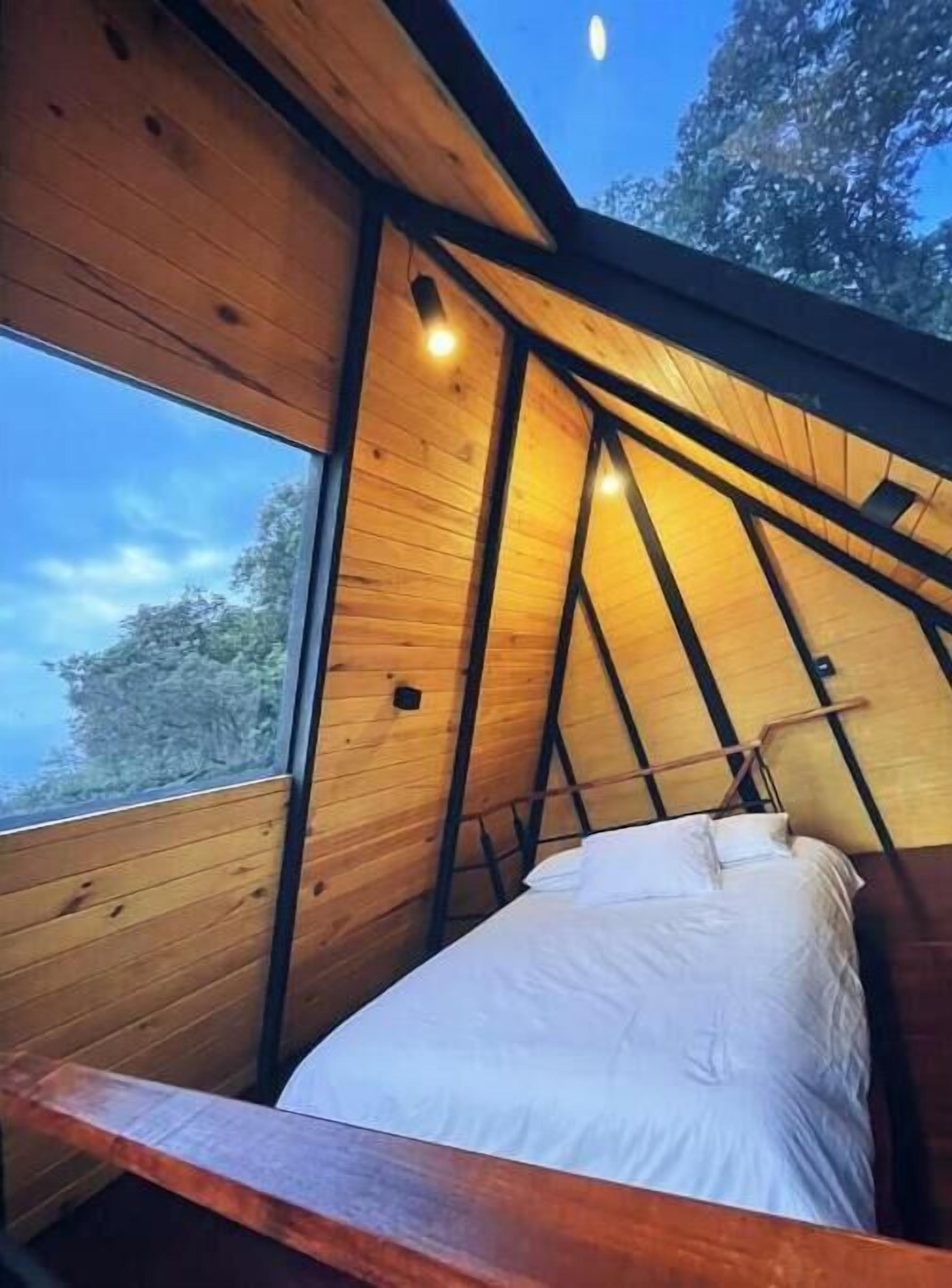 Ein Schlafzimmer mit Bett, Fenster und geneigter Deckenkonstruktion.
