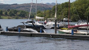 Un port de plaisance où sont amarrés plusieurs bateaux, entouré d’un lac et avec des collines en arrière-plan.
