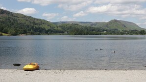 Un lac paisible, avec un kayak jaune sur la rive, entouré de collines verdoyantes et sous un ciel partiellement nuageux.
