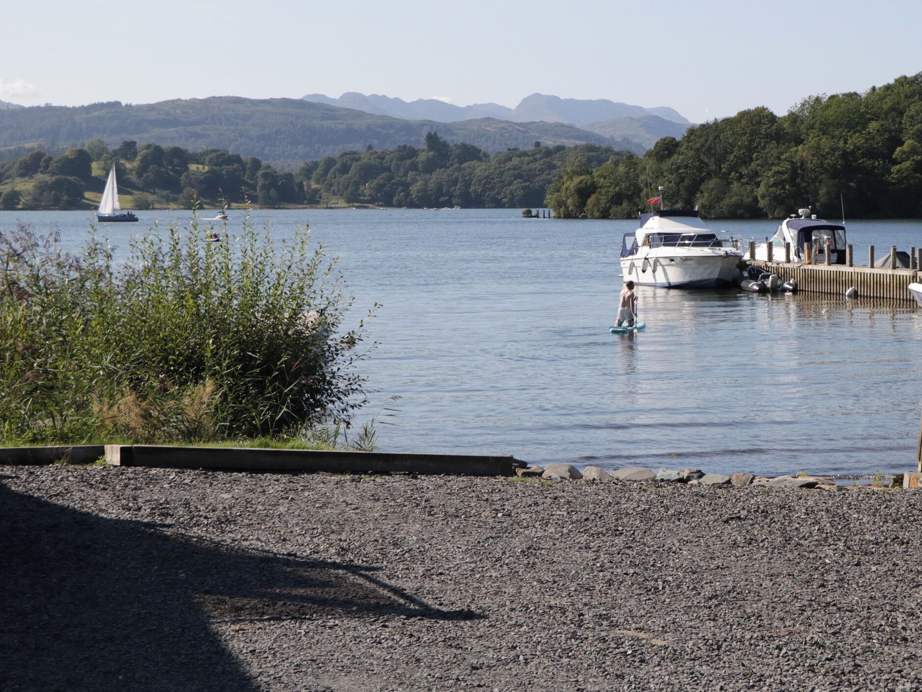 Un lago con barcos amarrados en un muelle, rodeado de montañas y vegetación.