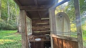 A rustic wooden structure with a bench, a small table, and a window. - Back in Time! River Log Cabin-Off Grid (Concord)