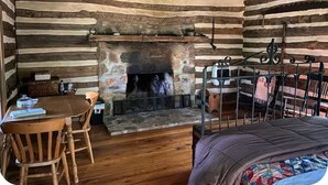 A log cabin interior with a stone fireplace, wooden furniture, and a bunk bed. - Back in Time! River Log Cabin-Off Grid (Concord)