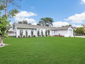A single-story house with a white exterior and a sloped roof. - 1.5 miles 5 min 🚗 to beaches, King Beds, BBQ, Nintendo Switch 🎮, Pet friendly 🐶. (Naples)