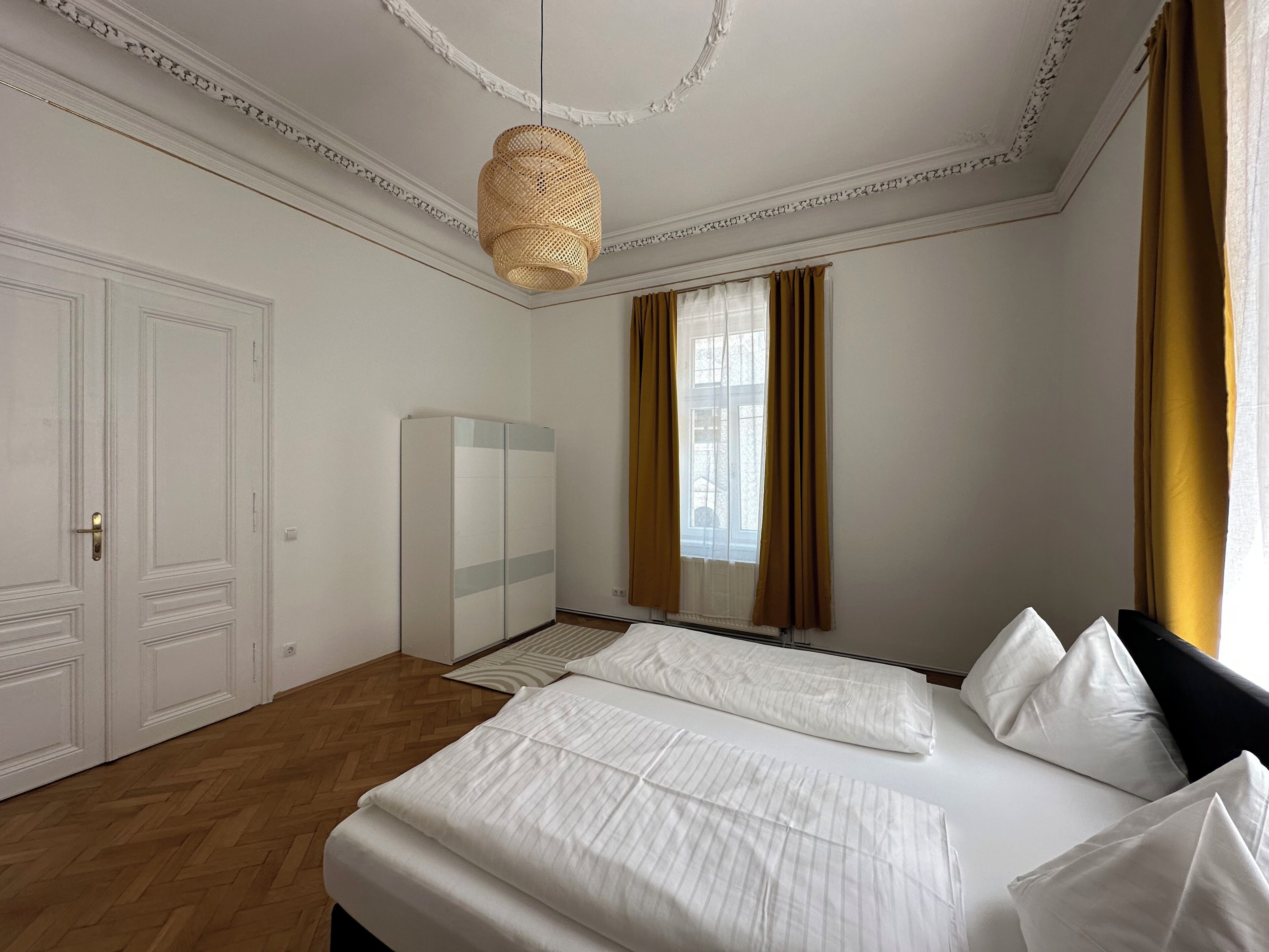 Ein Schlafzimmer mit einem großen Bett, einem Kleiderschrank, einem Spiegel und einer Hängeleuchte.
