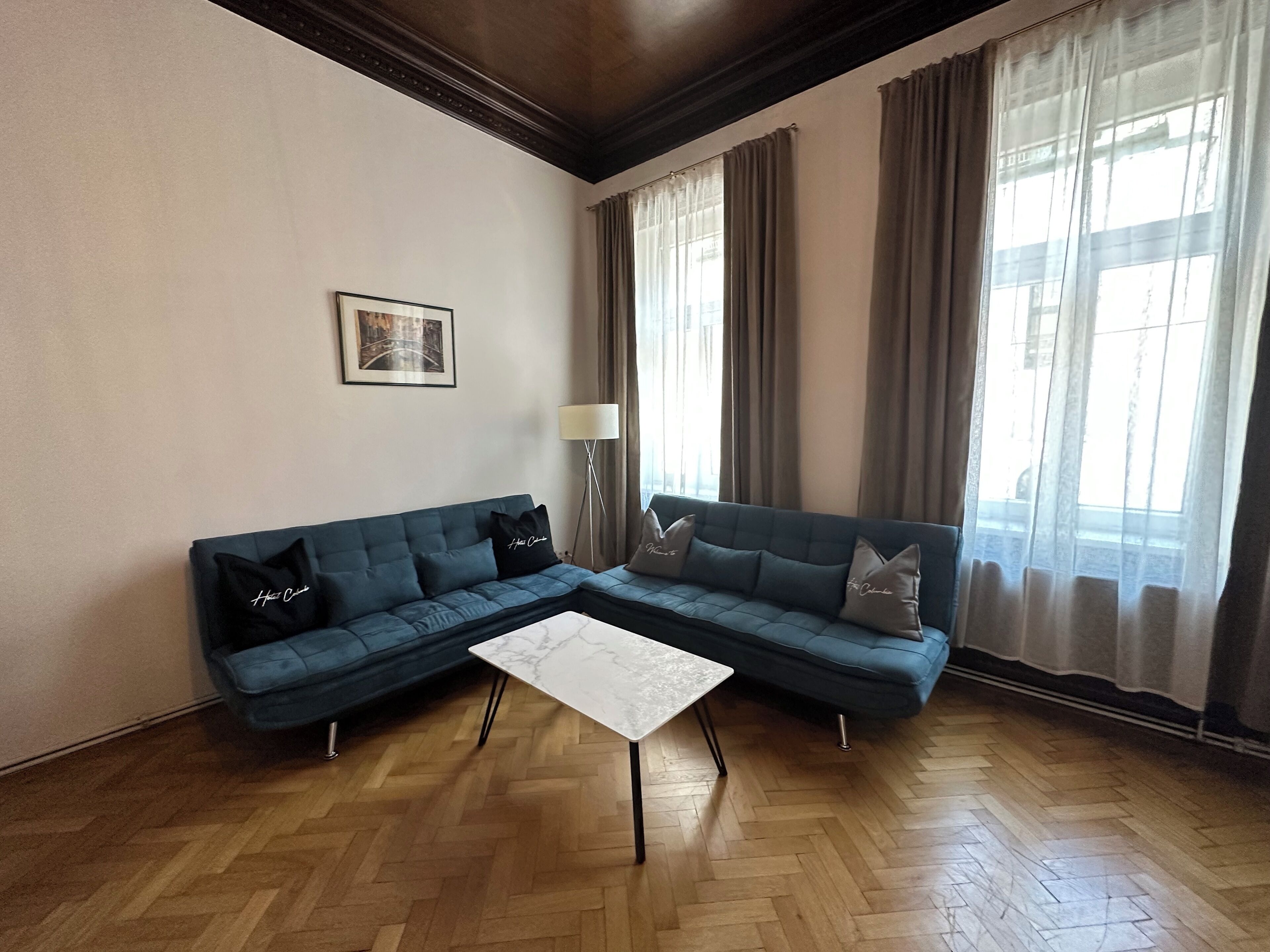 Ein Wohnzimmer mit einem blauen Sofa, einem weißen Couchtisch und einem Bild an der Wand.