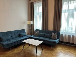A living room with a sectional sofa, a small table, and a floor lamp.