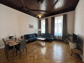 A modern living room with a sofa, dining table, and a TV. - Boutique Hotel Columbia (Vienna)