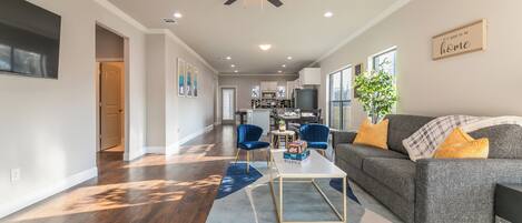 A spacious living area with a grey sofa, blue chairs, a coffee table, and a ceiling fan.