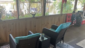 A covered outdoor seating area with wicker furniture and a view of a lake. - Charming water front cottage with central AC,quiet area in lovely Inverness (Inverness)
