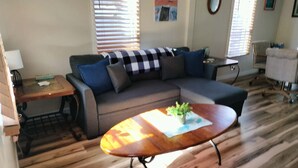 A living room with a sectional sofa, a wooden coffee table, and a small side table. - Charming water front cottage with central AC,quiet area in lovely Inverness (Inverness)