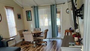 A spacious living area with a wooden floor, a ceiling fan, a dining table with chairs, a sofa, and a kitchen area with a counter and sink. - Charming water front cottage with central AC,quiet area in lovely Inverness (Inverness)