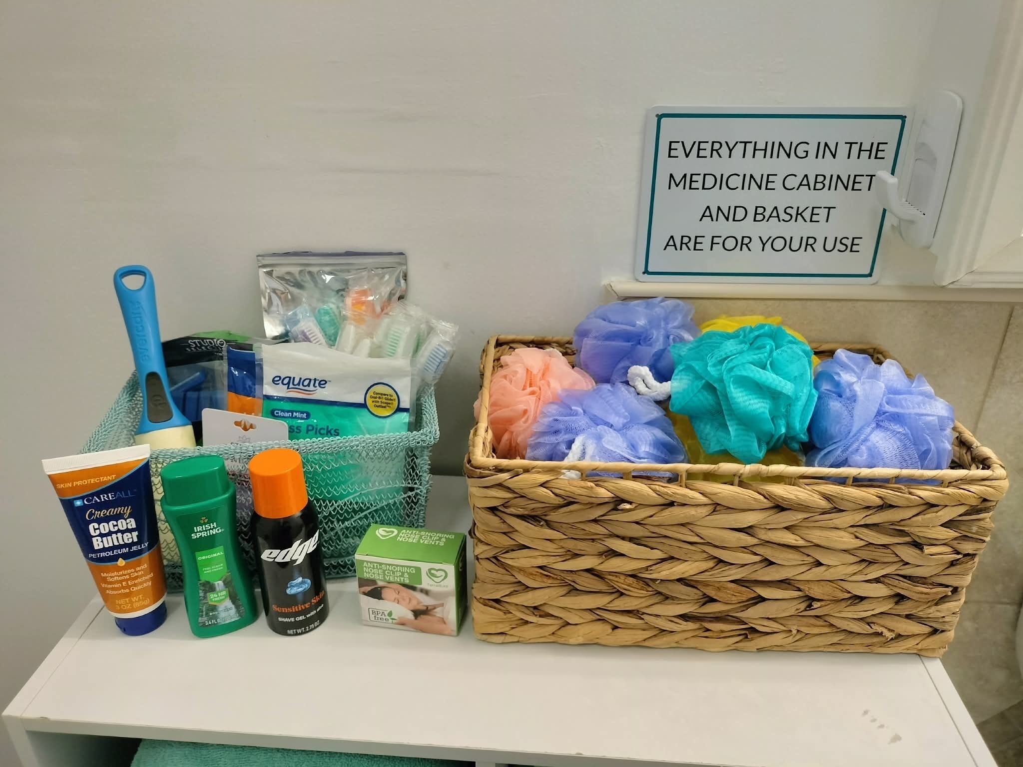 A medicine cabinet with various personal care items and a basket of colorful bath sponges.