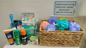 A medicine cabinet with various personal care items and a basket of colorful bath sponges.