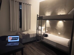 A bunk bed room with a laptop on a table, a window with curtains, and a wall-mounted light. - HOTEL SP CENTRO (São Paulo)
