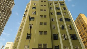 A multi-story building with a green facade, a visible entrance with a sign, and a street lamp in front. - HOTEL SP CENTRO (São Paulo)