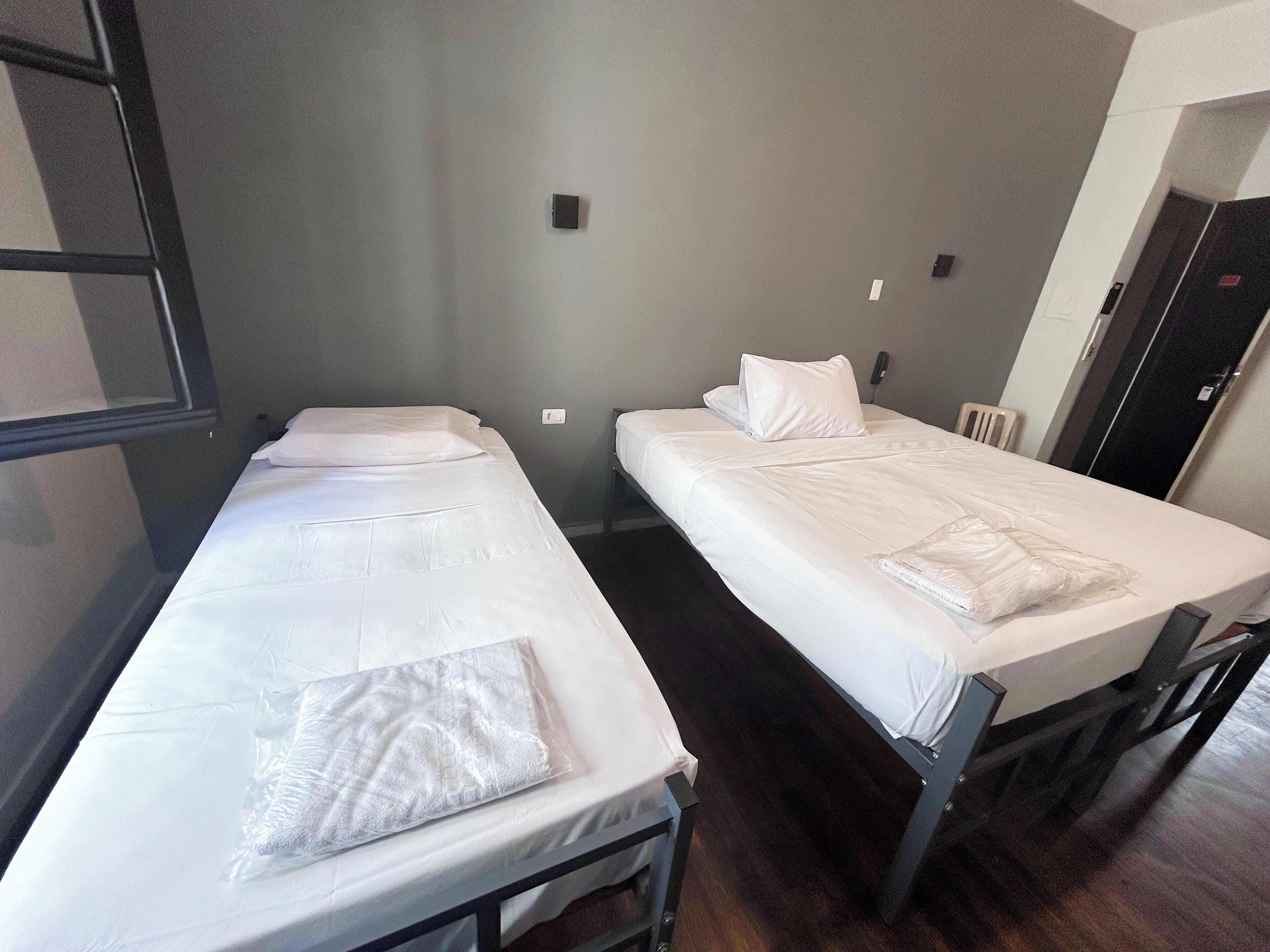 Two single beds with white linens in a room with a simple, functional design.