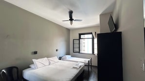 A hotel room with two beds, a ceiling fan, a window with curtains, and a desk. - HOTEL SP CENTRO (São Paulo)