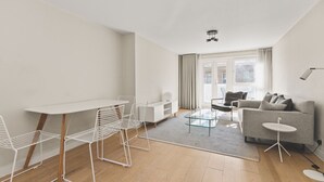 A modern, well-lit living room with a dining area, a sofa, and a coffee table. - Functional Belgravia 2BR Flat Near Victoria (London)