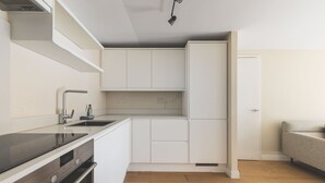 A modern kitchen with white cabinets, a black countertop, and a built-in oven. - Convenient 2BR/1BA Flat in Belgravia (London)