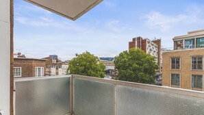 Un balcón con vistas a un paisaje urbano, que incluye edificios y árboles.