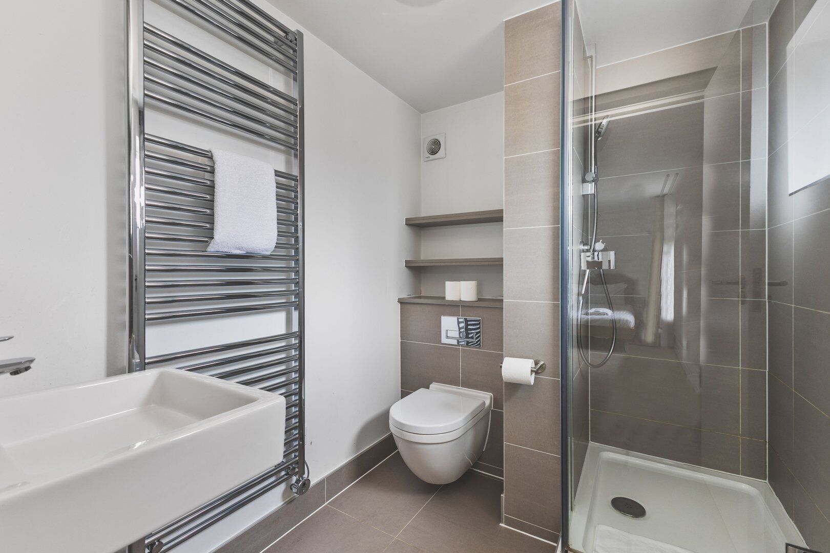 Een moderne badkamer met een douchecabine van glas, een witte badkuip en een toilet.