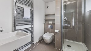 Un baño moderno con ducha envuelta en vidrio, una bañera blanca y un inodoro.