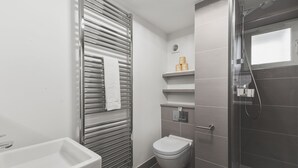Een moderne badkamer met een douchecabine van glas, een toilet en een bad.