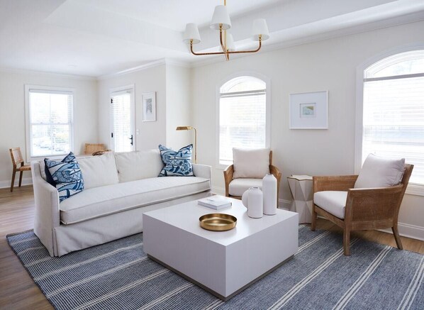 A modern living room with a white sofa, a coffee table, and wicker chairs. - May River Breeze! 3-story Townhouse in Old Town's Promenade (Bluffton)