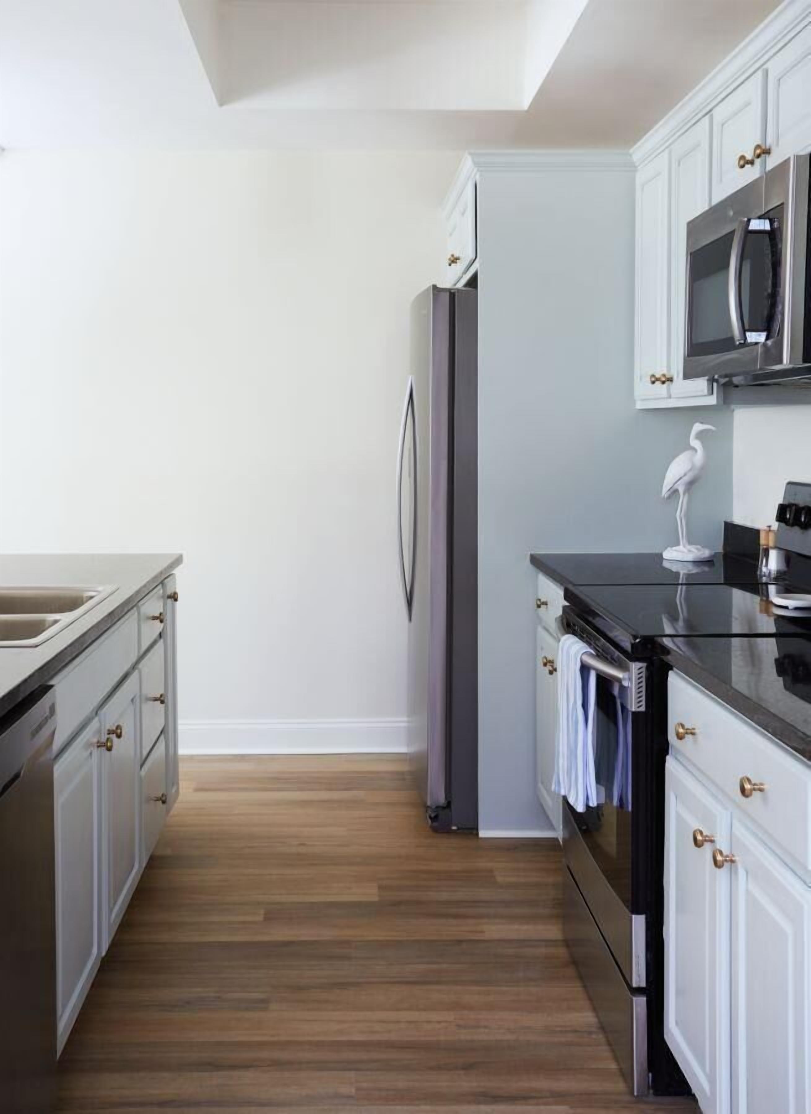 Una cocina moderna con armarios blancos, electrodomésticos de acero inoxidable y suelo de madera.