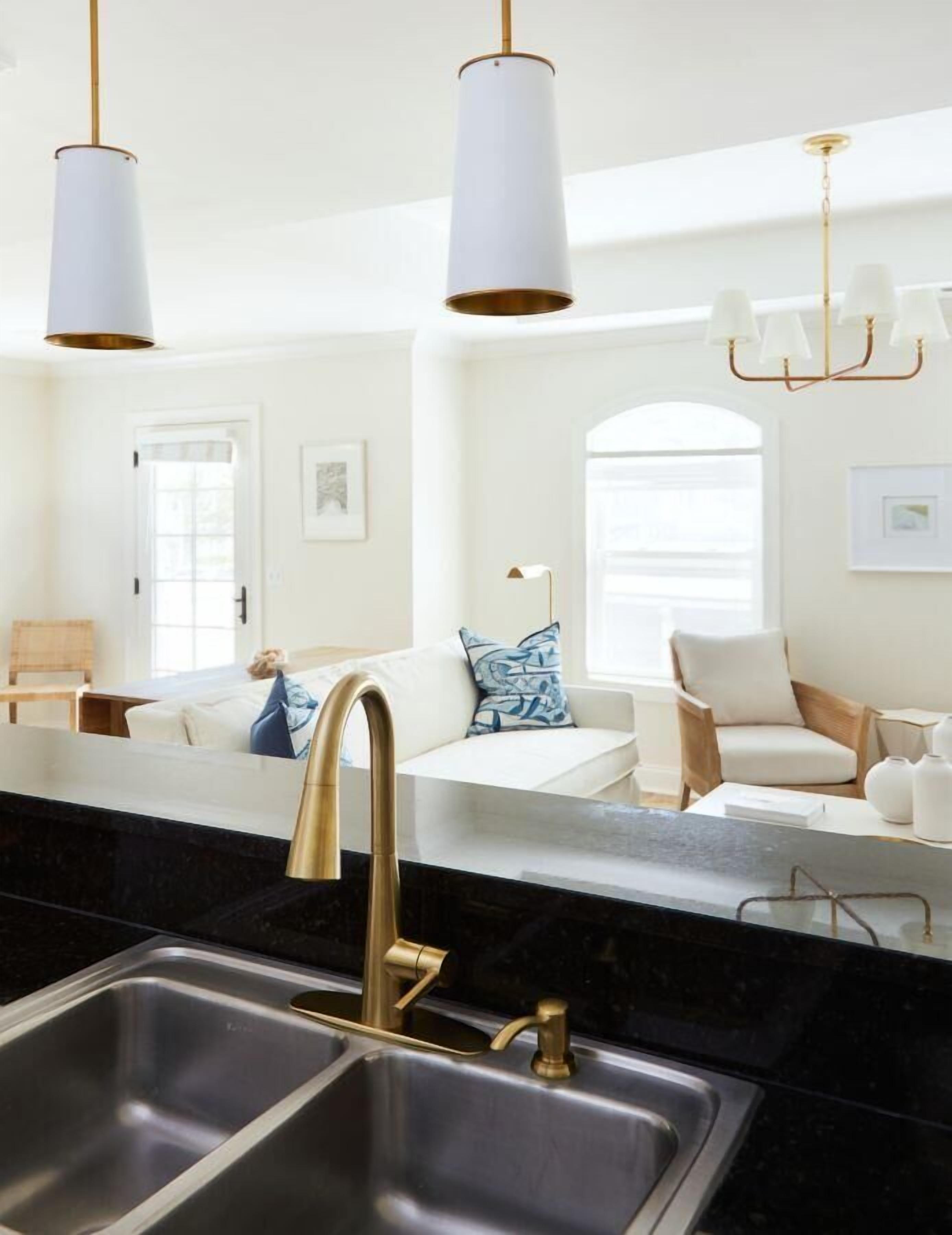 A modern kitchen with a double sink, gold faucets, and pendant lights.