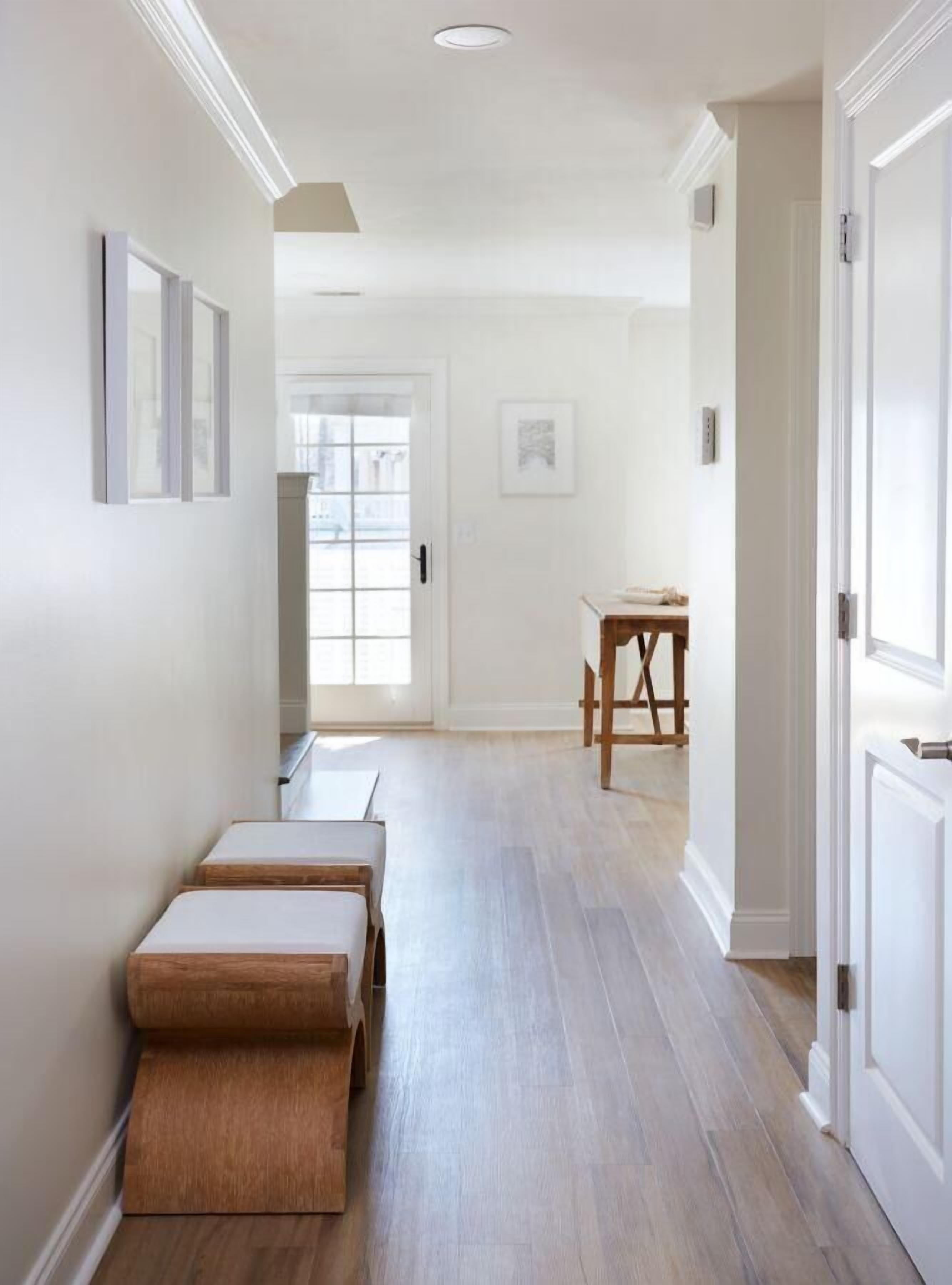Un couloir avec un banc en bois, une porte et une petite table avec une chaise.