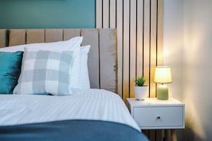 A neatly made bed with pillows, a bedside table with a lamp, and a small potted plant. - 2BR House By Eason Stays Short Lets Wythenshawe (Greater Manchester)