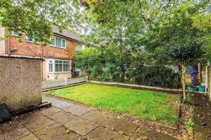 A backyard with a grassy lawn, a brick wall, and a fence.