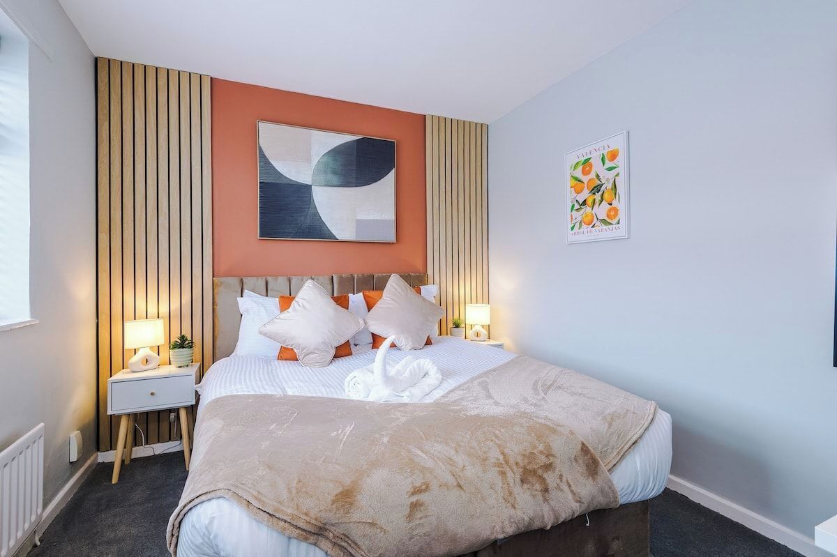 A hotel room with a bed, a nightstand, a lamp, and a wall art piece.