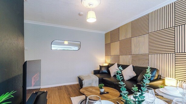 Een moderne woonkamer met een leren bank, een houten salontafel en een eethoek met witte borden en glazen.