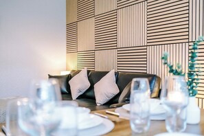 A dining area with a black leather sofa, white cushions, and a table set with plates and glasses. - 2BR House By Eason Stays Short Lets Wythenshawe (Greater Manchester)
