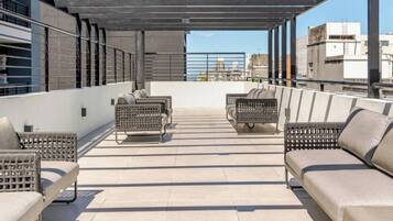 A rooftop terrace with outdoor seating and a view of the cityscape.