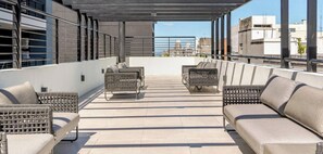 A rooftop terrace with outdoor seating and a view of the cityscape.