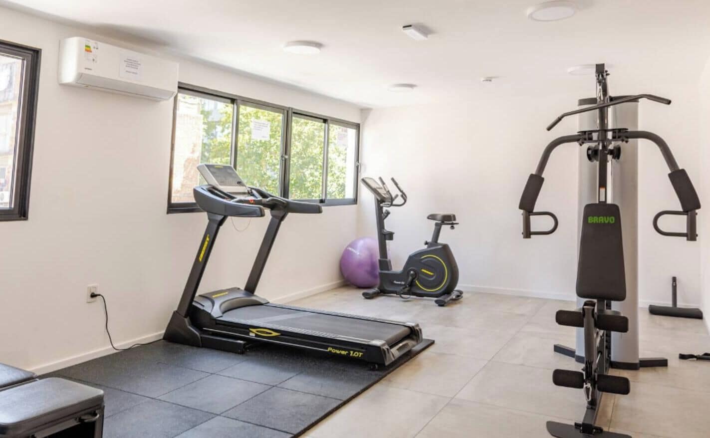 A gym with a treadmill, stationary bike, and weight machine.