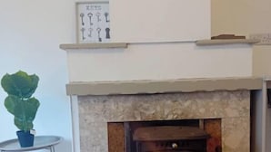Una chimenea con detalles de piedra, una mesita con una planta en maceta y un expositor de llaves sujeto a la pared.