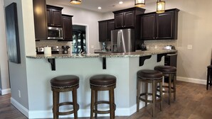 Una cocina moderna con gabinetes oscuros, electrodomésticos de acero inoxidable y una isla central con taburetes.