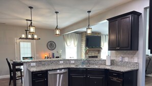 Una cocina moderna con armarios oscuros, encimeras de granito y electrodomésticos de acero inoxidable.