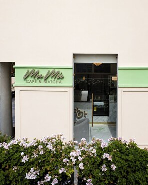 A building with a green sign reading 'Mlle Cafe & Matcha' and a glass door entrance. - Brada Collection Vendôme (Guadalajara)