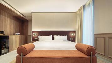A hotel room with a large bed, a wooden wardrobe, a flat-screen TV, and a large window with curtains.