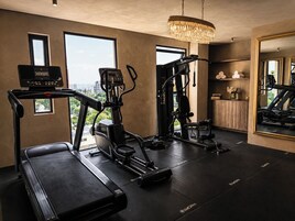 Un gimnasio con cintas de correr, una bicicleta estática y una máquina de pesas.
