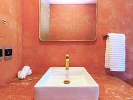 Un baño con un lavabo blanco, un grifo dorado, un espejo y un perchero para toallas.