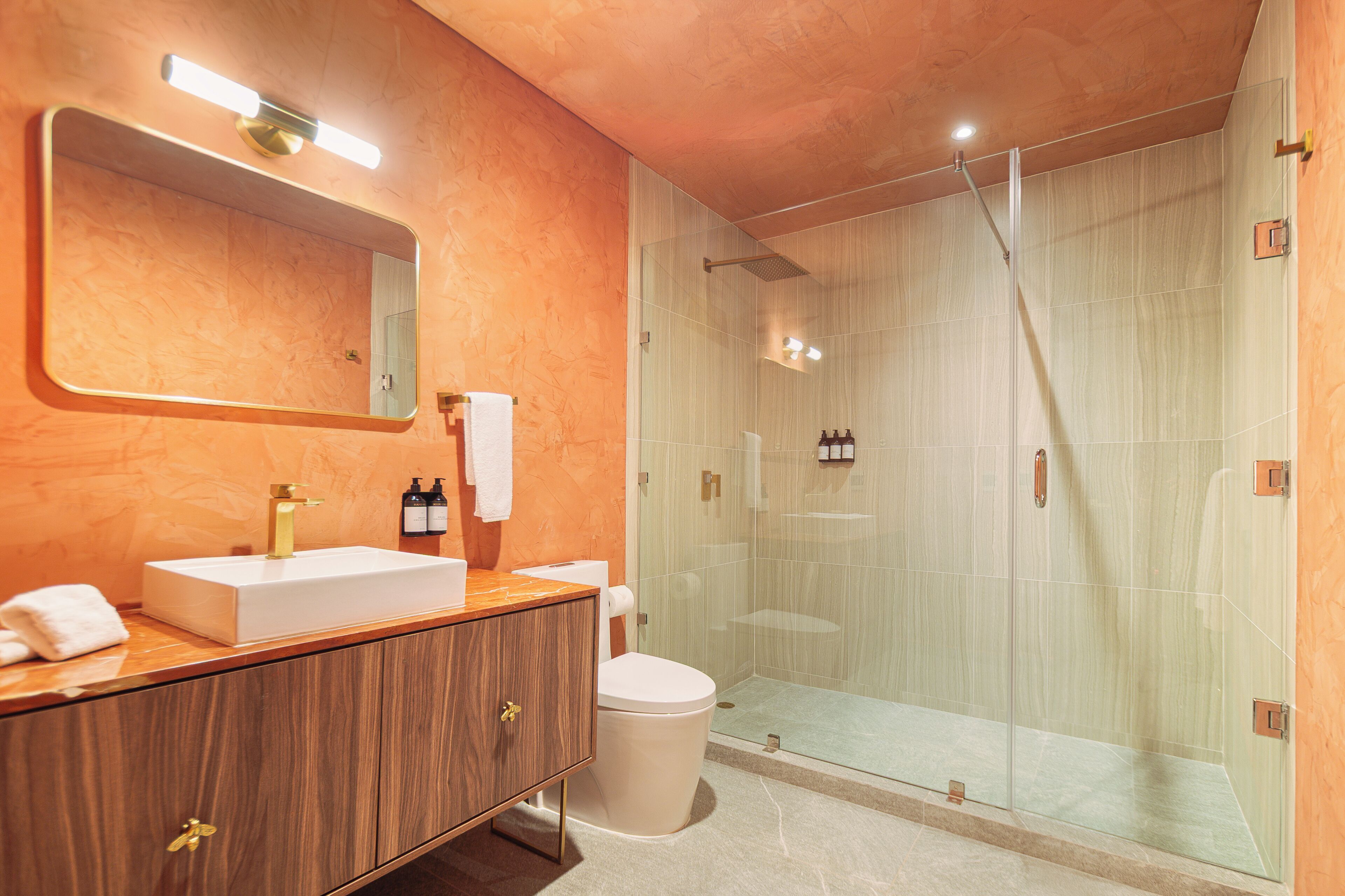 Un baño moderno con tocador, inodoro, cabina de ducha y un espejo grande.
