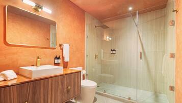 Un baño moderno con tocador, inodoro, cabina de ducha y un espejo grande.